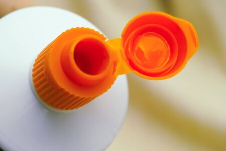 Open orange cap of toothpaste tube. Closeup.