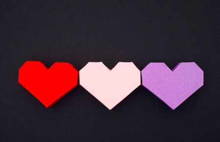 Three origami hearts on black background.の写真素材