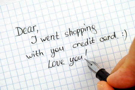 Woman hand with pen wriring note - Dear, I went shopping with  your credit card. Love you!の写真素材
