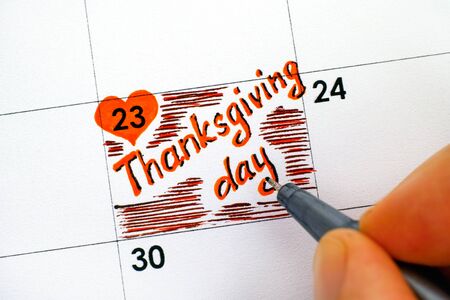 Woman fingers with black pen writting reminder Thanksgiving day.の写真素材