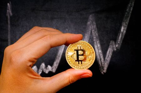 Tambov, Russian Federation - December 27, 2017 Woman hand with golden Bitcoin virtual money against...