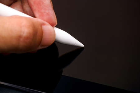 Person fingers with white digital pencil touching on digital tablet. Close-up.の写真素材
