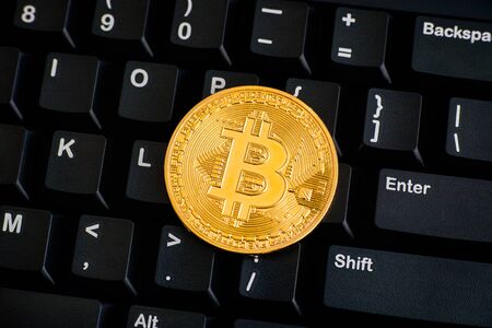 Golden Bitcoin virtual money on black keyboard. Close-up.の写真素材