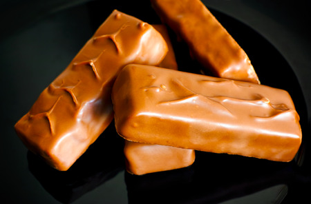 Four chocolate bars on black plate.の写真素材