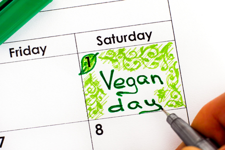 Woman fingers with pen writing reminder Vegan Day in calendar. 1 November. Close-up.の写真素材