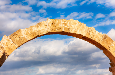 Ancient stone arch against cloudy sky.の写真素材