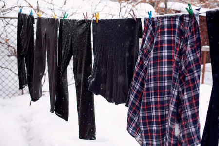 Washed laundry hanging outdoors in snowfall. Winter time.の写真素材