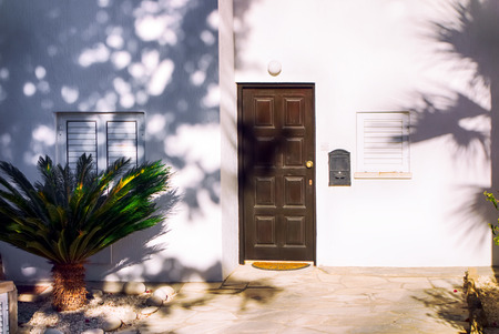 White mediterranean house with brown door , close windows and frontage.の写真素材