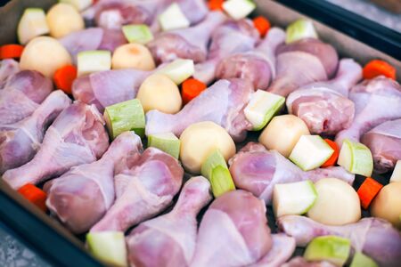 Chicken legs with vegetables on baking tray ready to cook.の写真素材