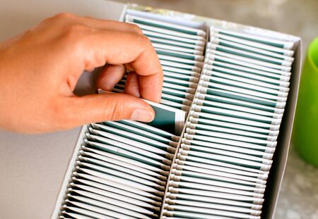 Person hand taking out tea bag from box. Closeup.