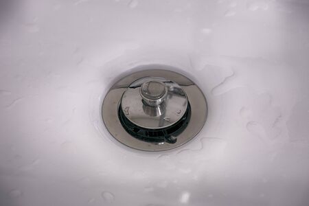 Close-up of sink drain with stopper.