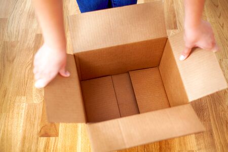 Woman hands opens empty cardboard box.