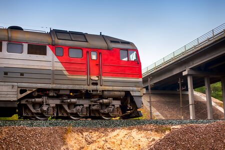 Locomotive riding on railways under the bridge. Close up.