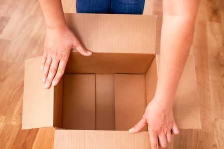 Woman hands opening empty cardboard box. Close up.