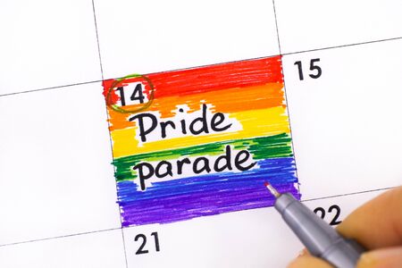Woman fingers with pen writing reminder Pride Parade in calendar. Close-up.の写真素材
