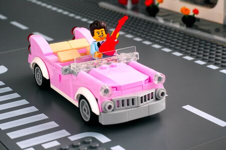 Tambov, Russian Federation - January 22, 2020 Lego rock n roll star minifigure with guitar in pink 1950s-style convertible on the road. Studio shot.のeditorial素材
