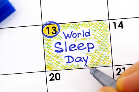 Woman fingers with pen writing reminder World Sleep Day in calendar. March 13.の写真素材
