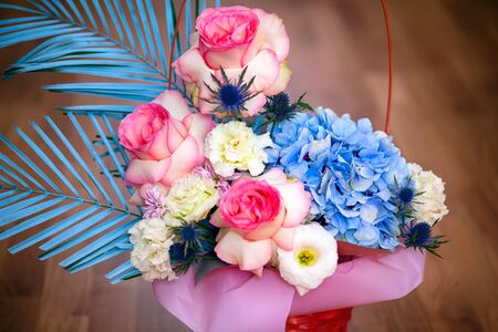 Beautiful floral composition with roses, eustoma and hydrangea in basket. Wooden background.の写真素材