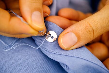 Woman sewing a button. Close-up.
