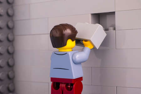 Tambov, Russian Federation - June 07, 2020 Lego man minifigure with brick ready to finishing gray wallのeditorial素材