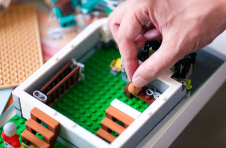 Tambov, Russian Federation - June 20, 2020 Close-up of person hand making Lego house interior on the table with instructions. Shallow depth of fieldのeditorial素材