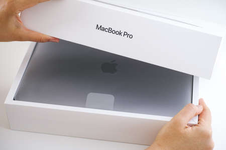 Tambov, Russian Federation - July 09, 2020 Woman hands opening box with MacBook Pro. Studio shot.