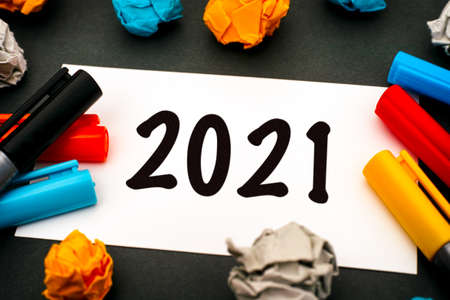 Numbers 2021 on paper blank with colour pens and crumpled paper. Black background. Close-up.の写真素材