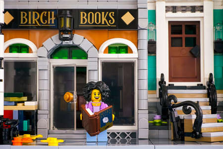 Tambov, Russian Federation - June 26, 2020 Lego woman minifigure with book stands near Birch Books building. Studio shot.のeditorial素材