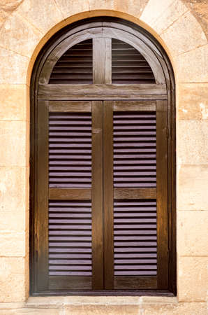 Arched window with closed shutters on stone wall. Close-upの写真素材