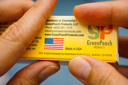 Tambov, Russian Federation - July 09, 2016 GreenPeach Products box in woman hands. Focus on text Made in USA and flag.のeditorial素材