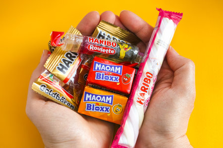 Tambov, Russian Federation - January 06, 2021 Woman palms full of Haribo candies. Yellow background.のeditorial素材