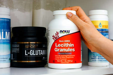 Tambov, Russian Federation - January 25, 2021 Woman hand taking bottle of Lecithin Granules by Now out of a cupboardのeditorial素材