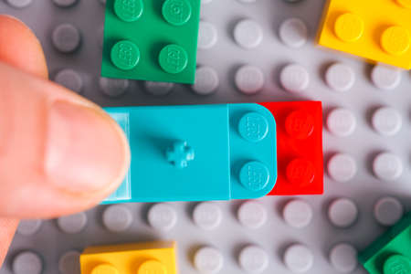 Tambov, Russian Federation - January 17, 2021 Person hand with Lego teal Brick Separator removing red brick from gray baseplateのeditorial素材