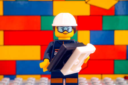 Tambov, Russian Federation - January 17, 2021 Lego engineer minifigure with blueprint standing against Lego brick wall backgroundのeditorial素材