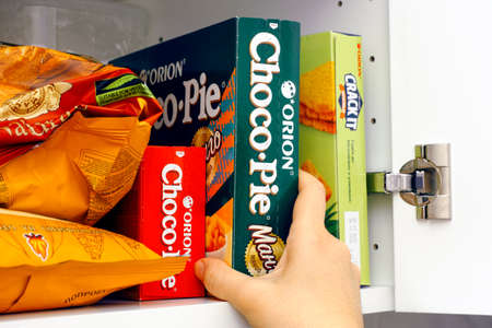 Tambov, Russian Federation - January 25, 2021 Woman taking Orion Choco-Pie Mango box out of a...