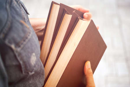 A Woman holds three books in her hands