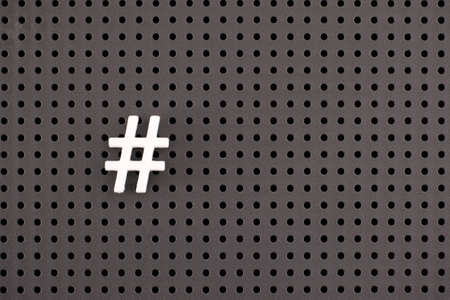White Hashtag symbol on a gray pegboard