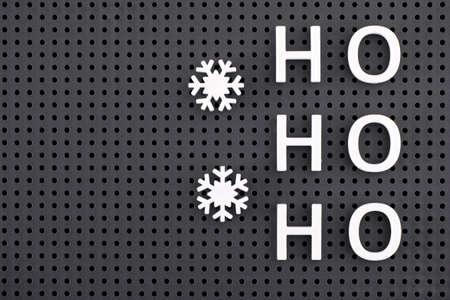 Ho, Ho, Ho and snowflakes spelled out with white letters and signs on a gray pegboard. Close-up