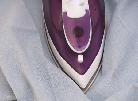 A violet iron ironing blue linen textileの写真素材