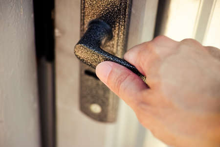 A person hand opening a gate door with a doorknobの写真素材