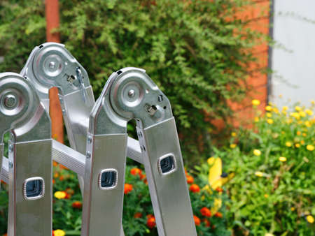 Close-up of a top of aluminium multipurpose hinged ladder standing outdoors.の写真素材