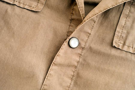 Close-up of button on a beige shirt.の写真素材