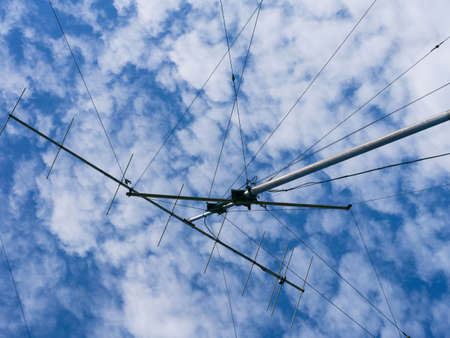 VHF radio antenna with a stay ropes against a cloudy sky