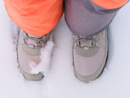 Kids feet in winter shoes standing on snow