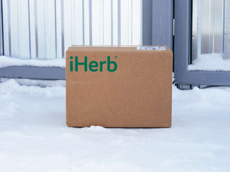 Tambov, Russian Federation - February 05, 2022 iHerb cardboard box delivered to a house gate. Winter...