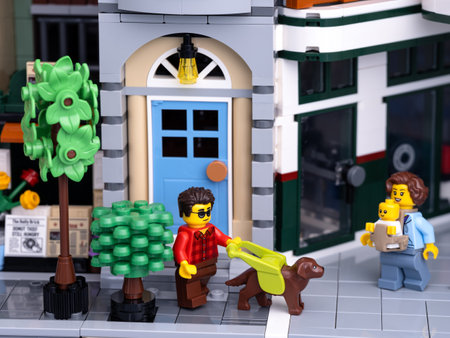 Tambov, Russian Federation - January 08, 2022 A Lego visually impaired man minifigure with a guide dog walking on a city street with a Lego mother with a baby walking towards him.のeditorial素材