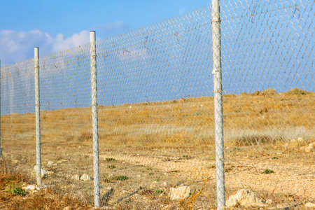 A chain link fence with a field behind it.