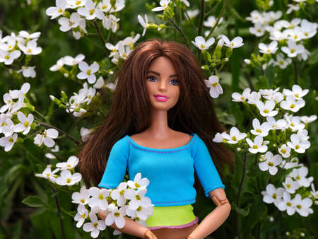 Tambov, Russian Federation - April 30, 2022 A Brunette Barbie doll standing among white flowers...