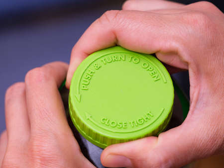 A woman removing a green cap from a bottle. Close-up