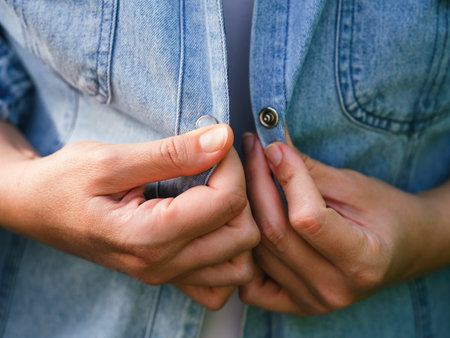 A woman buttoning a denim jacket. Close-upの写真素材